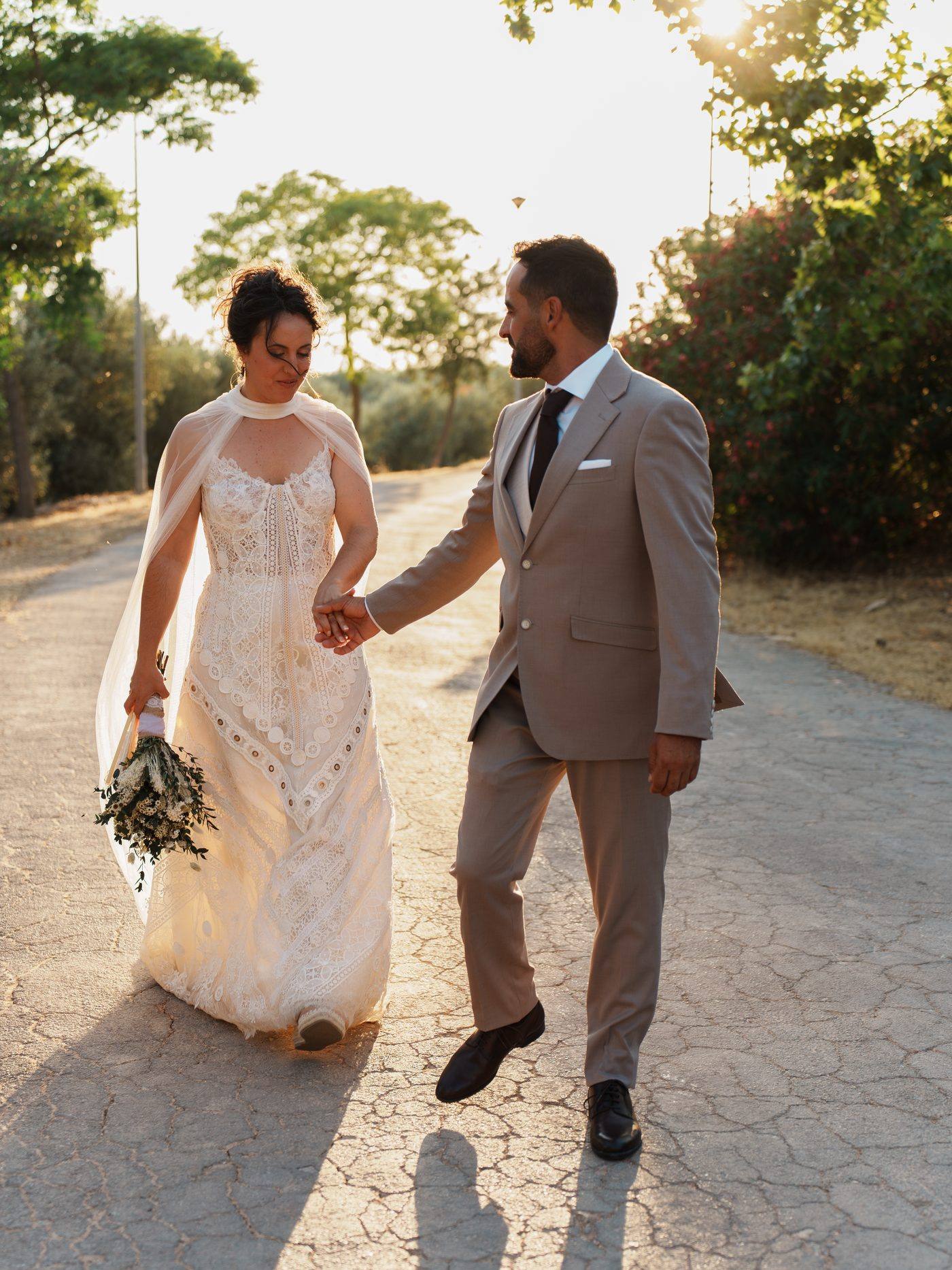 Los novios caminando por un camino al atardecer
