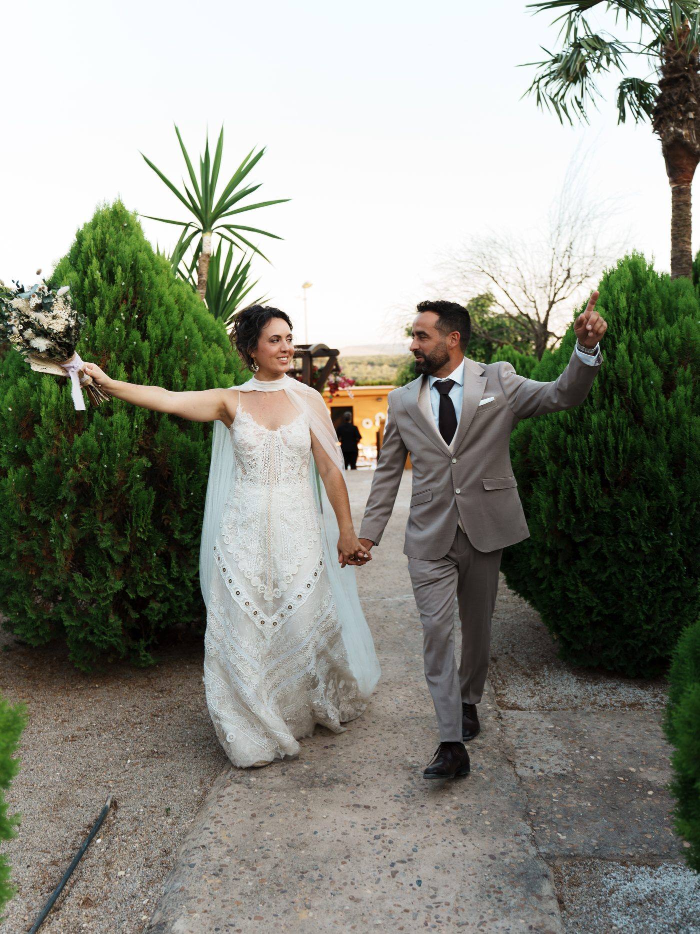 Los novios entrando al jardín con los brazos en alto