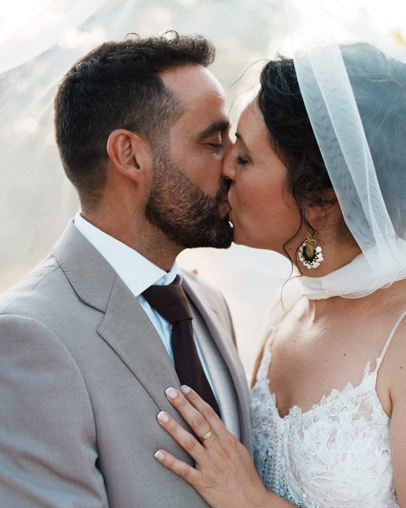 Los novios besándose bajo el velo