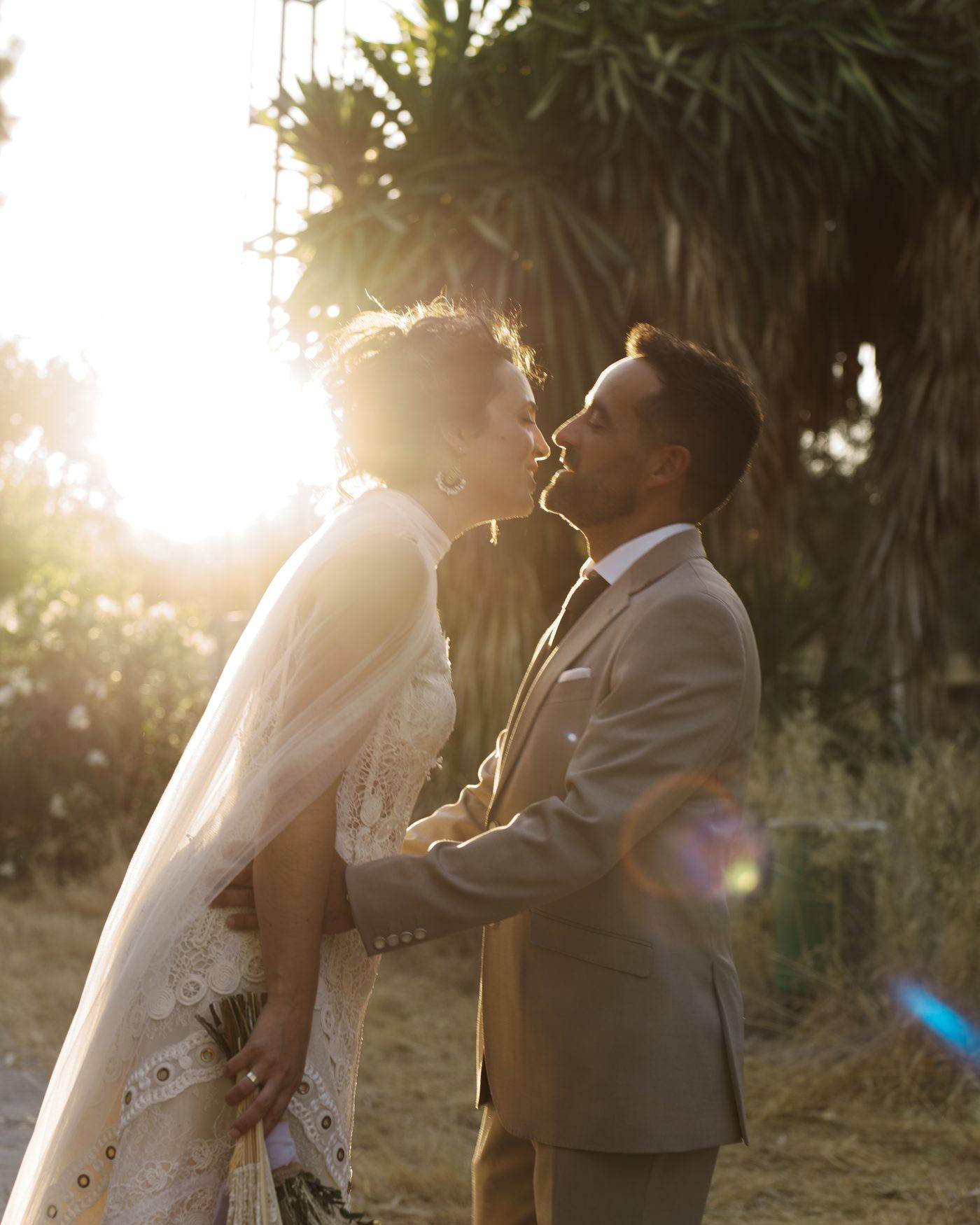 Los novios a punto de besarse, con destellos de sol